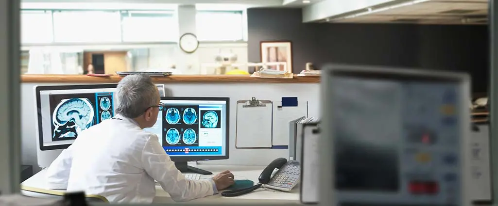 A neurologist looking at MRI scans of the brain on his computer in his office